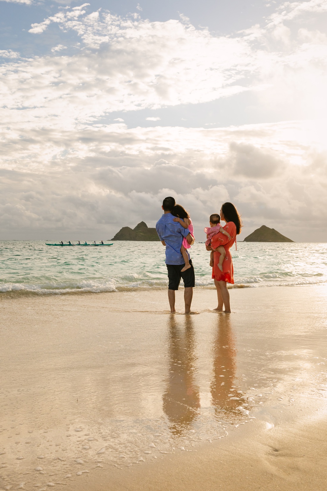 family watches outrigger off the mokulua islands at lanikai beach