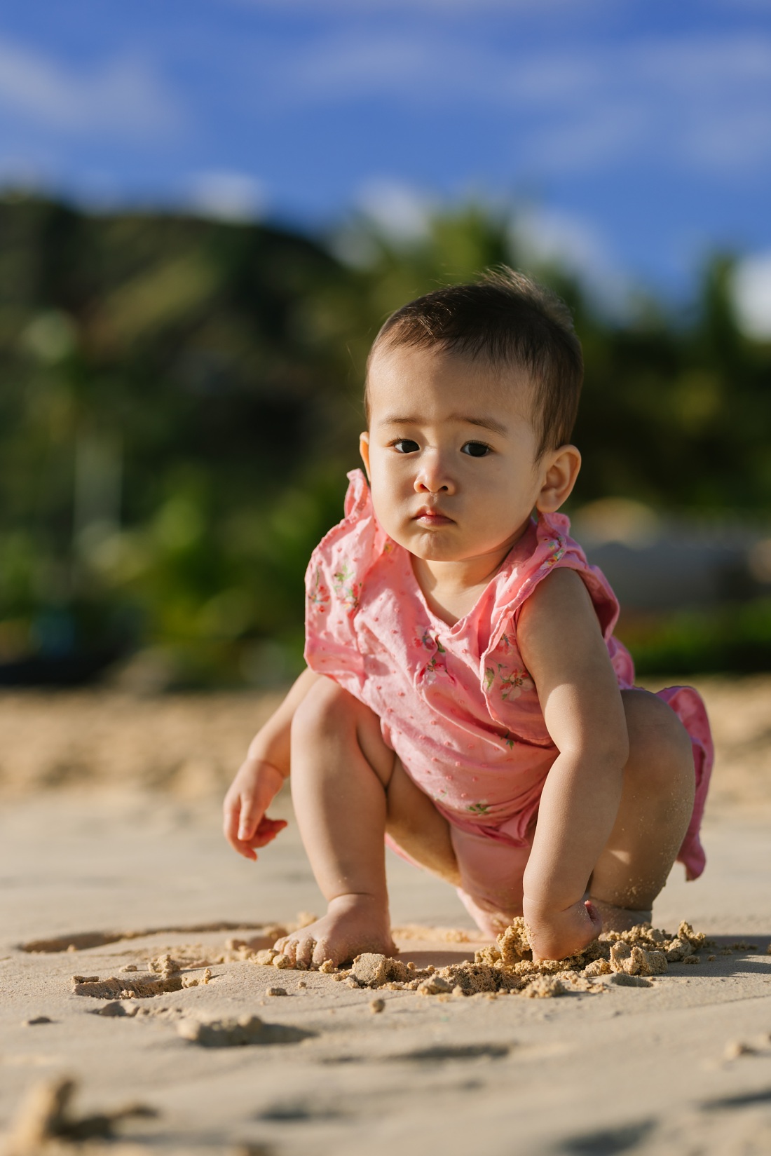 baby girl digs in the sand in hawaii