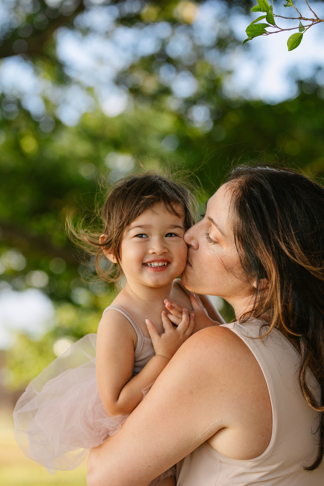 mom kisses toddler daughter on the cheek during a hawaii family photo session