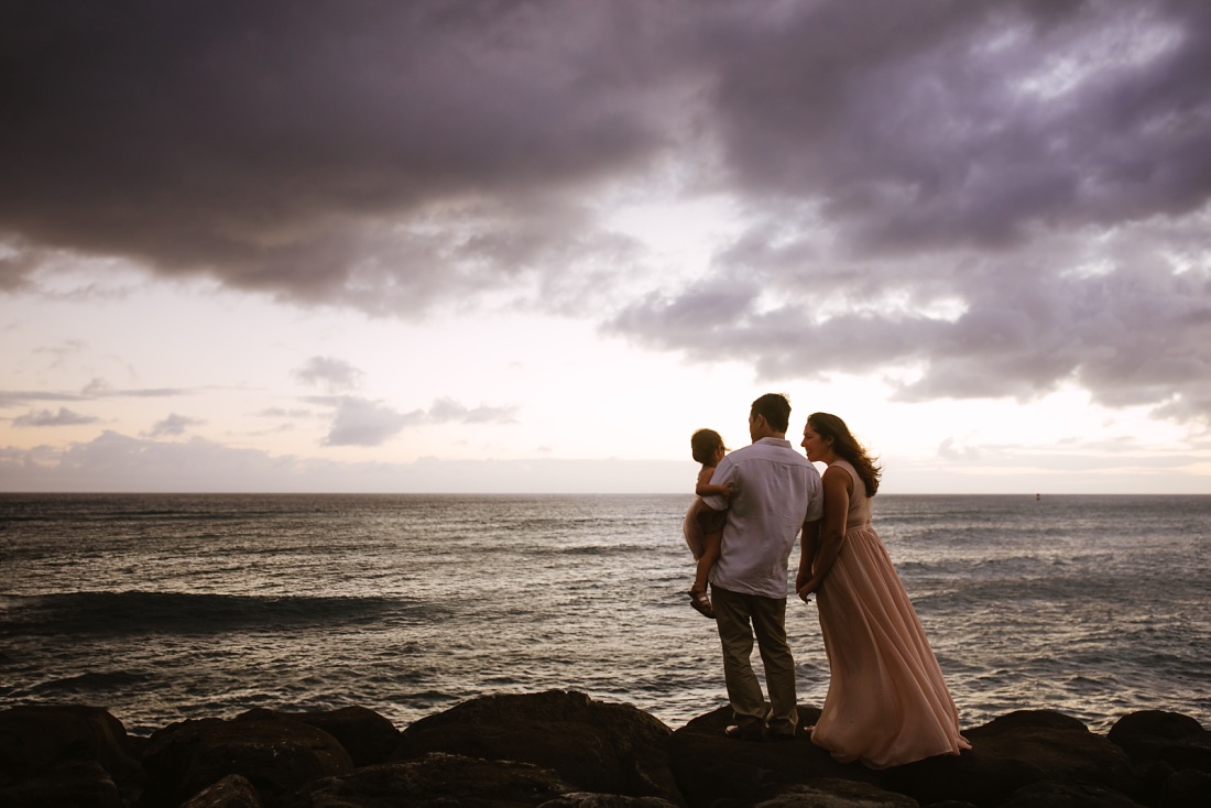 family watches the waves at twilight in honolulu