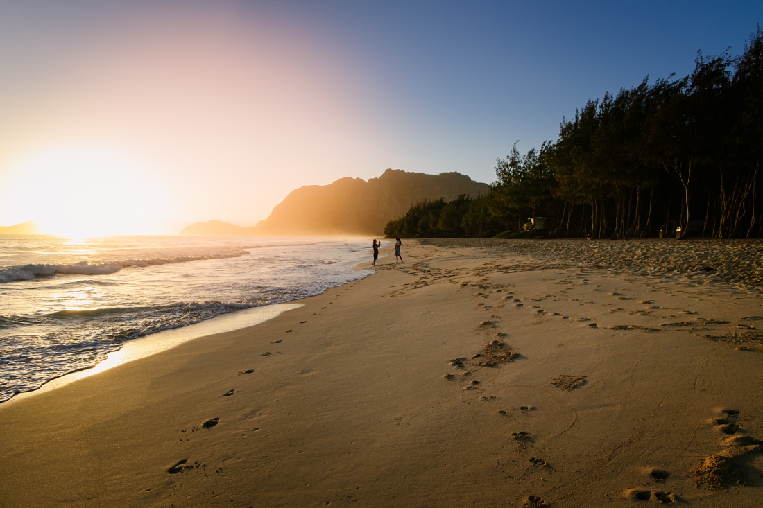 family walking on the beach at sunrise in waimanalo oahu during a photo session
