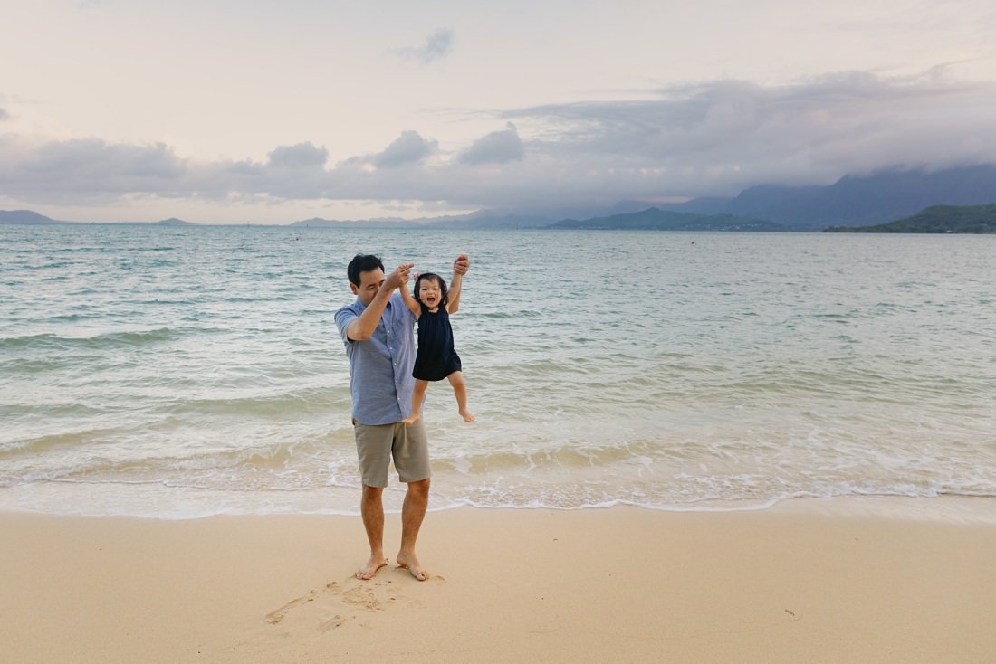 dad and baby playing at the beach with kaneohe bay in the background