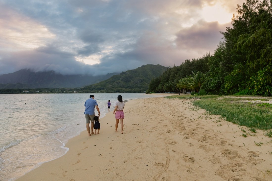 family walking on the beach in hawaii at sunset
