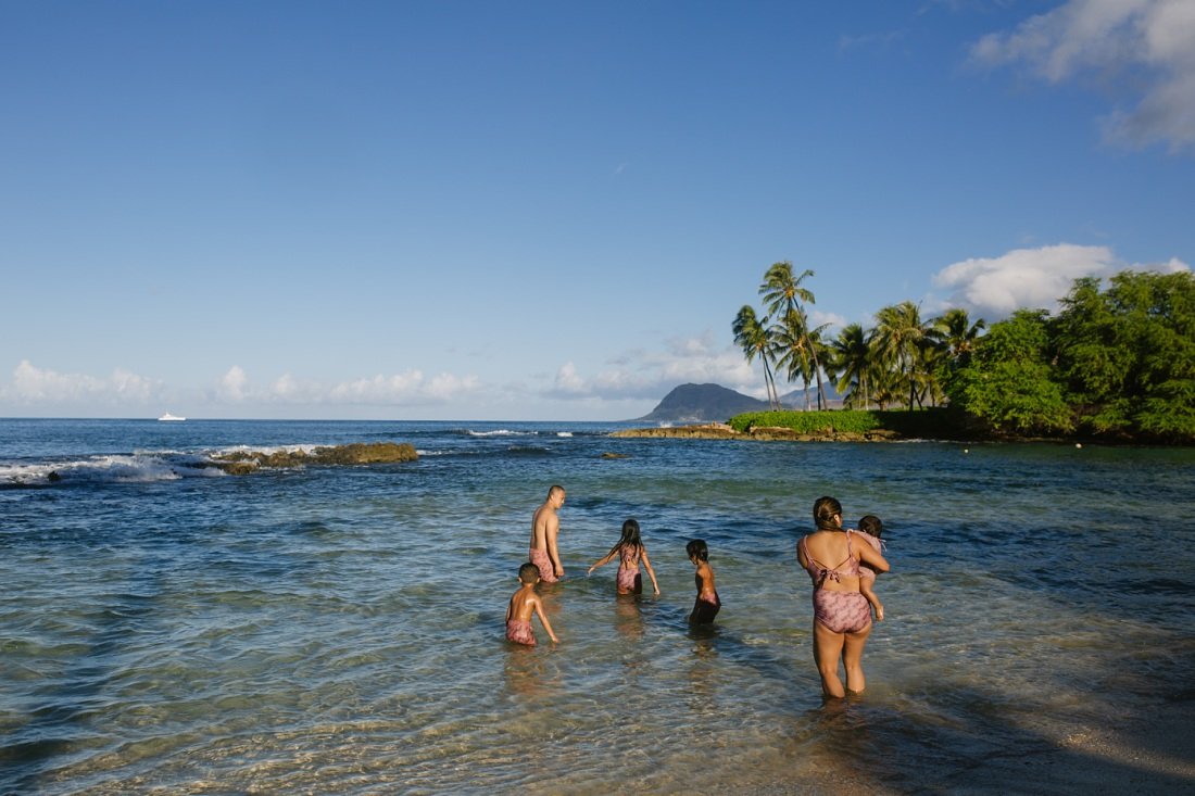 family playing in the blue water of koolina lagoon oahu
