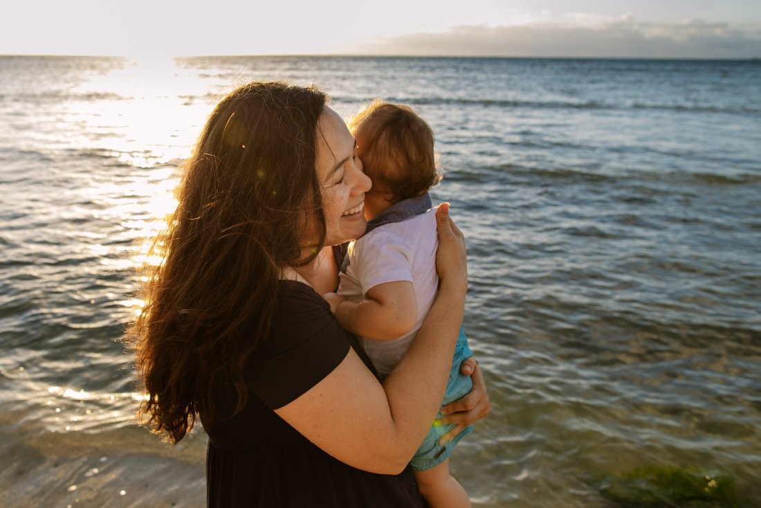 mom hugs baby tightly during a sunrise photo session in oahu
