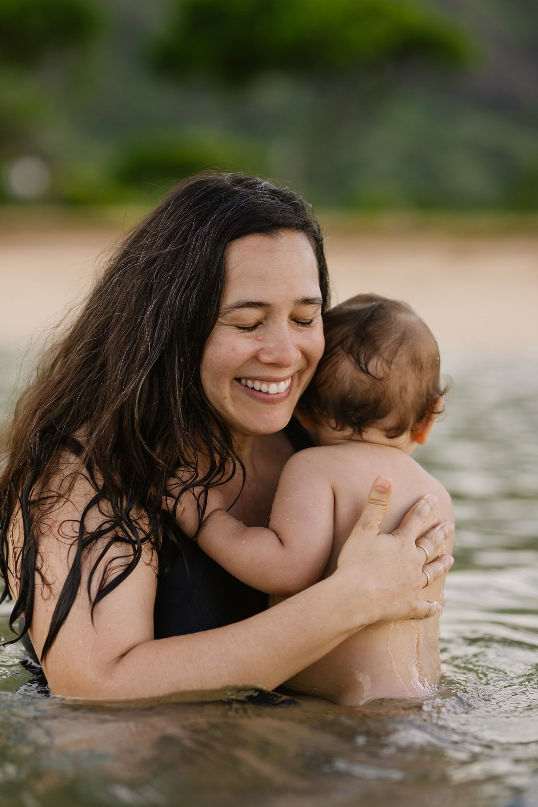 oahu baby photographer captures mom and baby snuggling at the beach in oahu