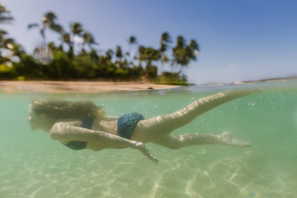 girl swimming under the water during koolina family photos by best hawaii photographer