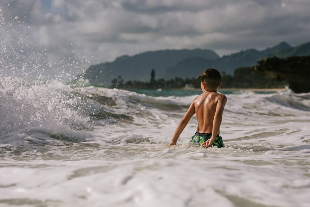 little boy at pounders beach in laie oahu during a family photo session