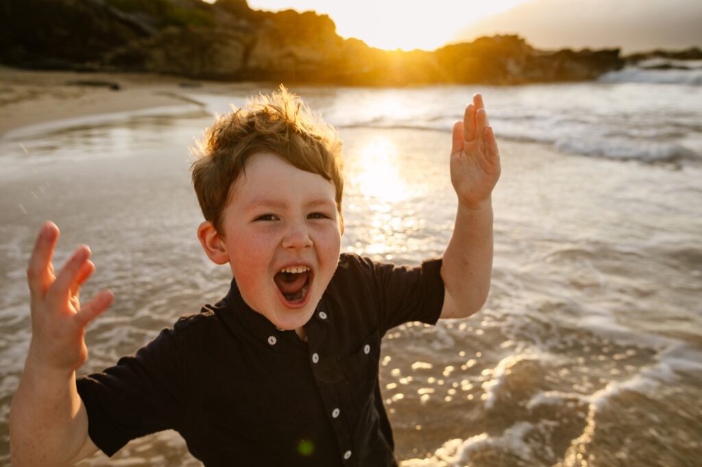 a boy yells with excitement at sunset in maui