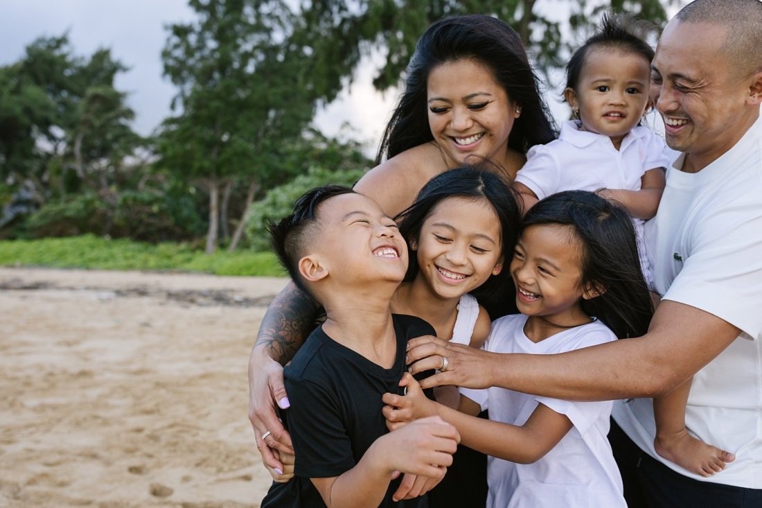 happy family sharing a hug during a beach photo session in hawaii