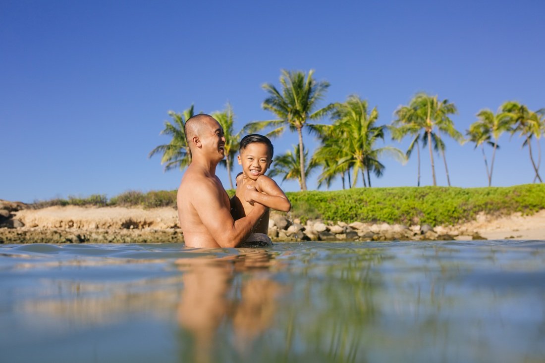 dad plays with son in the calm waters of koolina beach