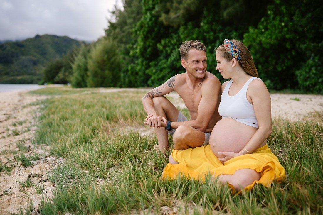couple lounges on the beach during a maternity photoshoot