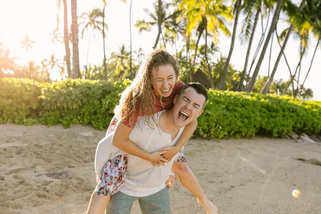 couple laughing hard with palms behind captured by fun family photographers in Oahu