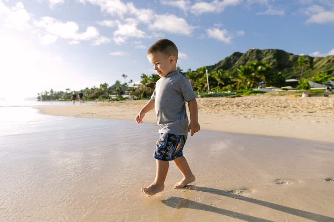 Family photographers in Oahu capture toddler boy playing in the surf at lanikai beach
