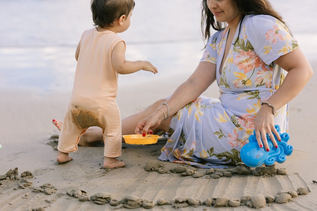 mom and baby play with sand toys