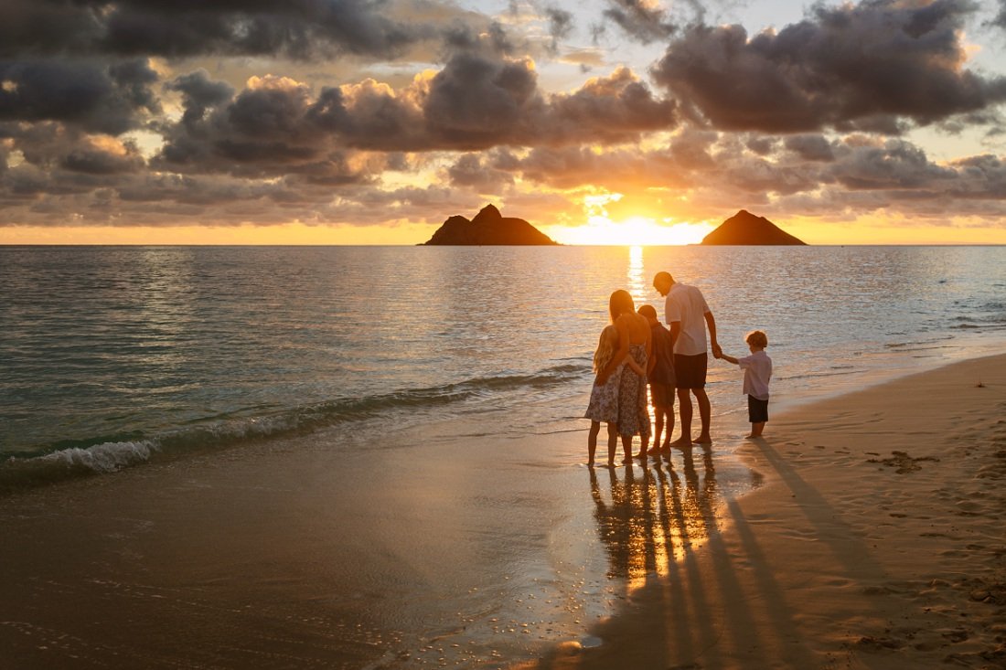 family watching sunrise over the mokes from Lanikai beach