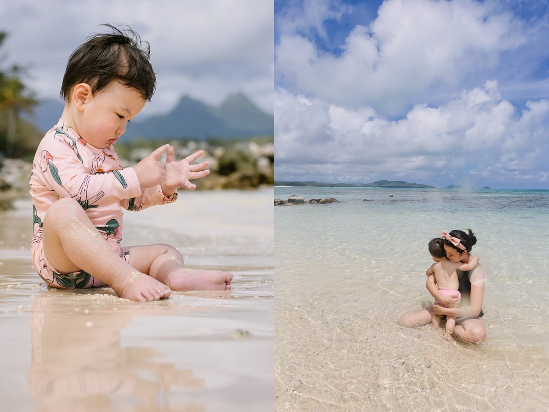 baby and mom snuggle on beautiful sandy beach in hawaii