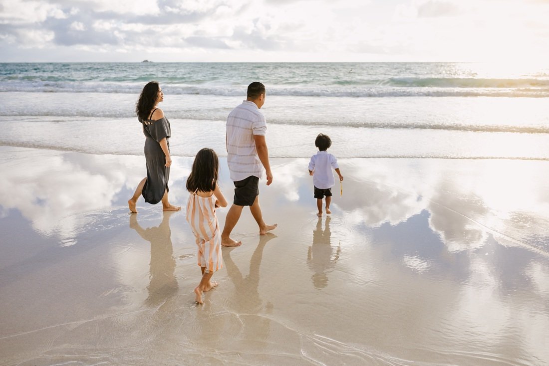 family walking on kailua beach with reflections of the sky on the water