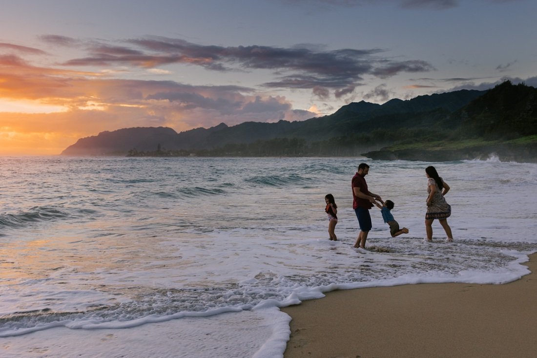 family playing in the surf at sunrise during a laie photo session
