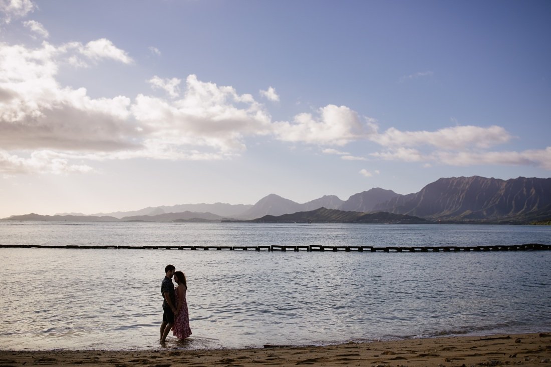 couple snuggles against the backdrop of kaneohe bay in oahu
