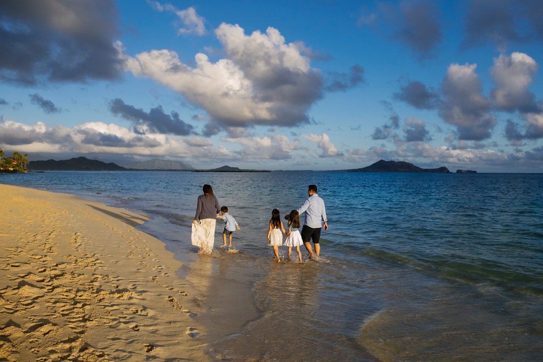 family walking along empty lanikai beach at sunrise
