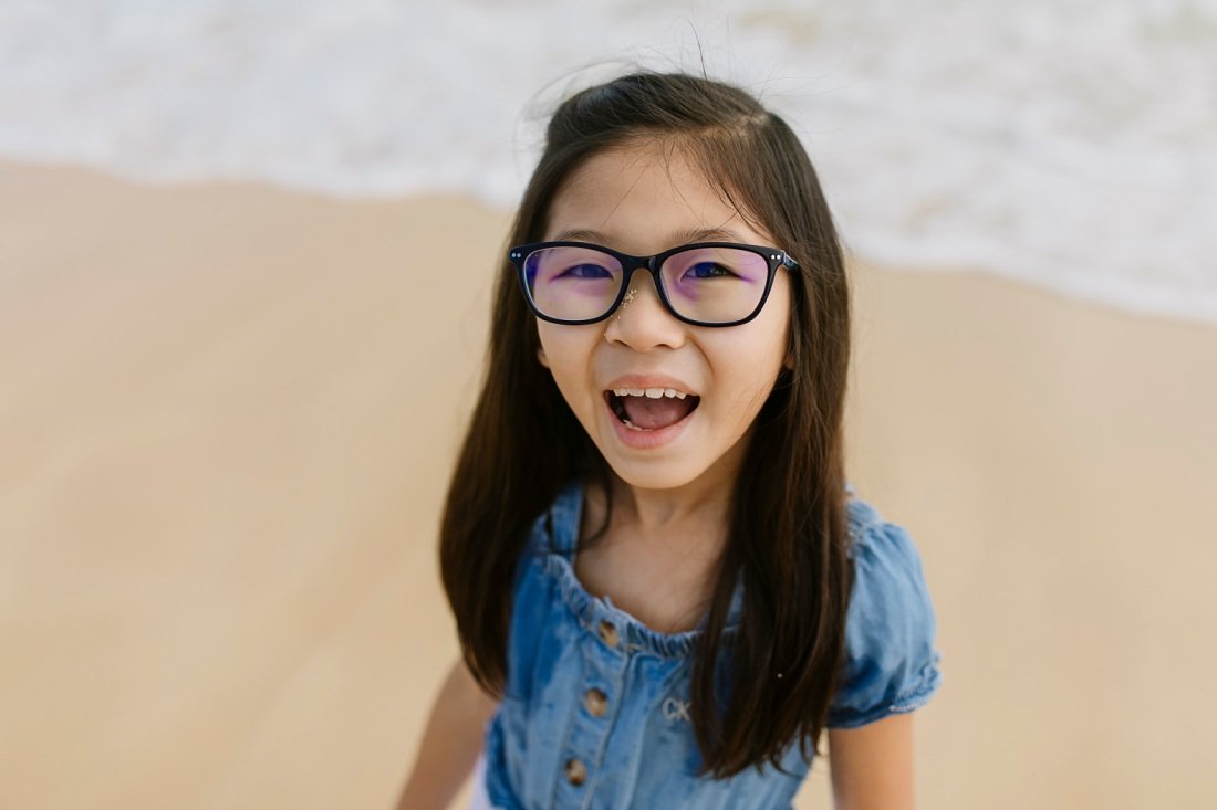 closeup of girl with glasses laughing at the beach