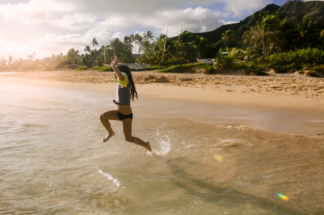 girl leaping into the ocean at lanikai beach
