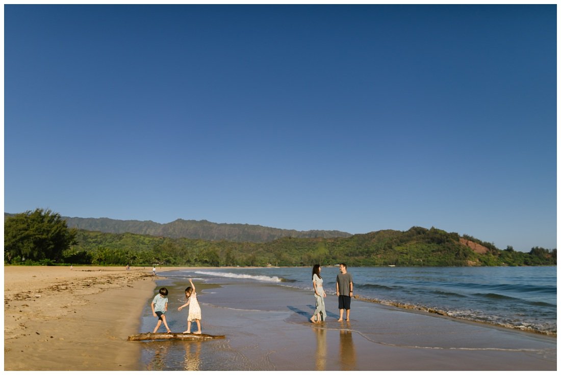 family plays on the beach during family photos at sunrise hanalei bay kauai