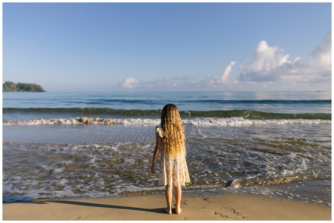 girl with long hair watching the waves in hanalei bay during family photoshoot