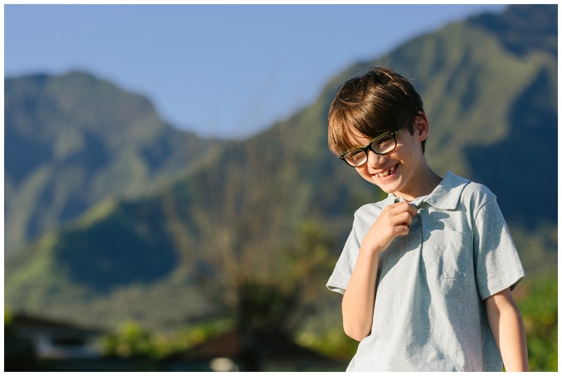 photo of a boy with glasses laughing and kauai mountains in the background