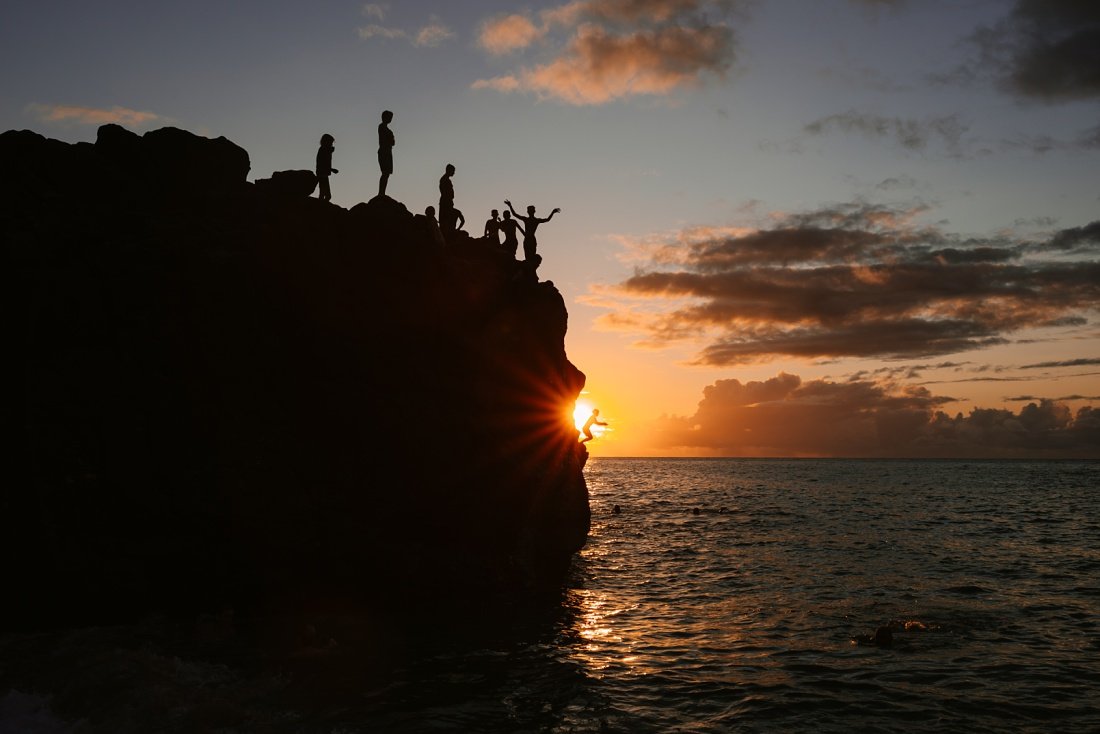 jumping off the waimea bay rock at sunset on north shore of oahu