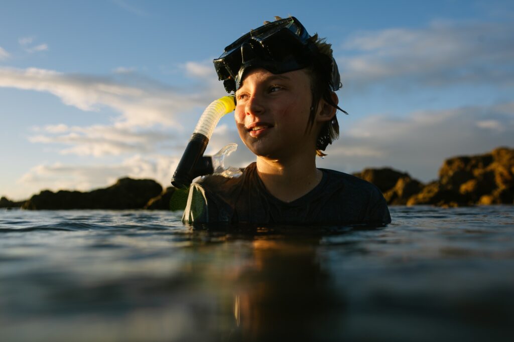 boy snorkeling at sharks cove at sunset