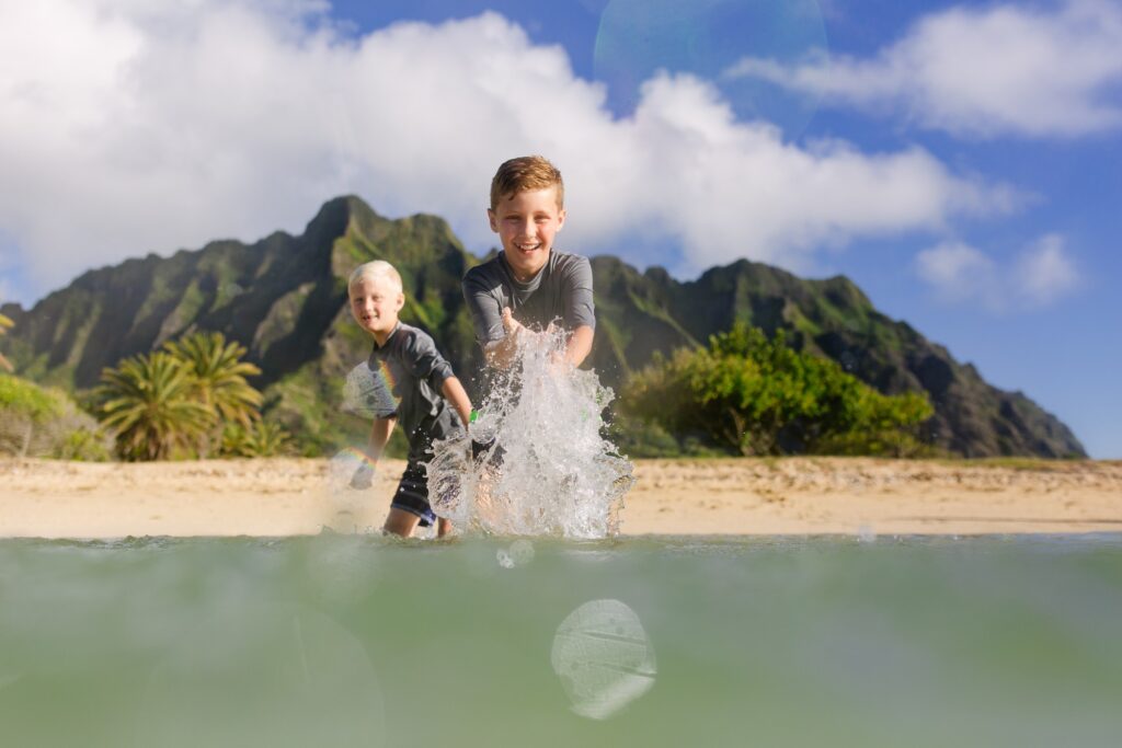 boys splashing in the water at kualoa beach park