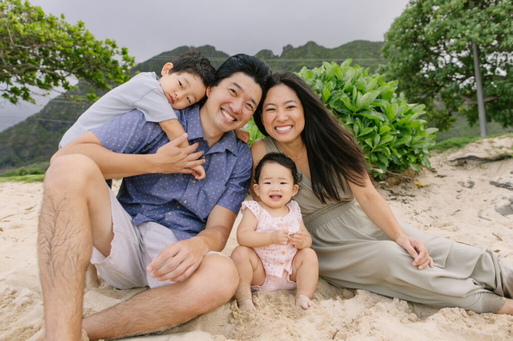 family smiling on hawaii beach for family photos