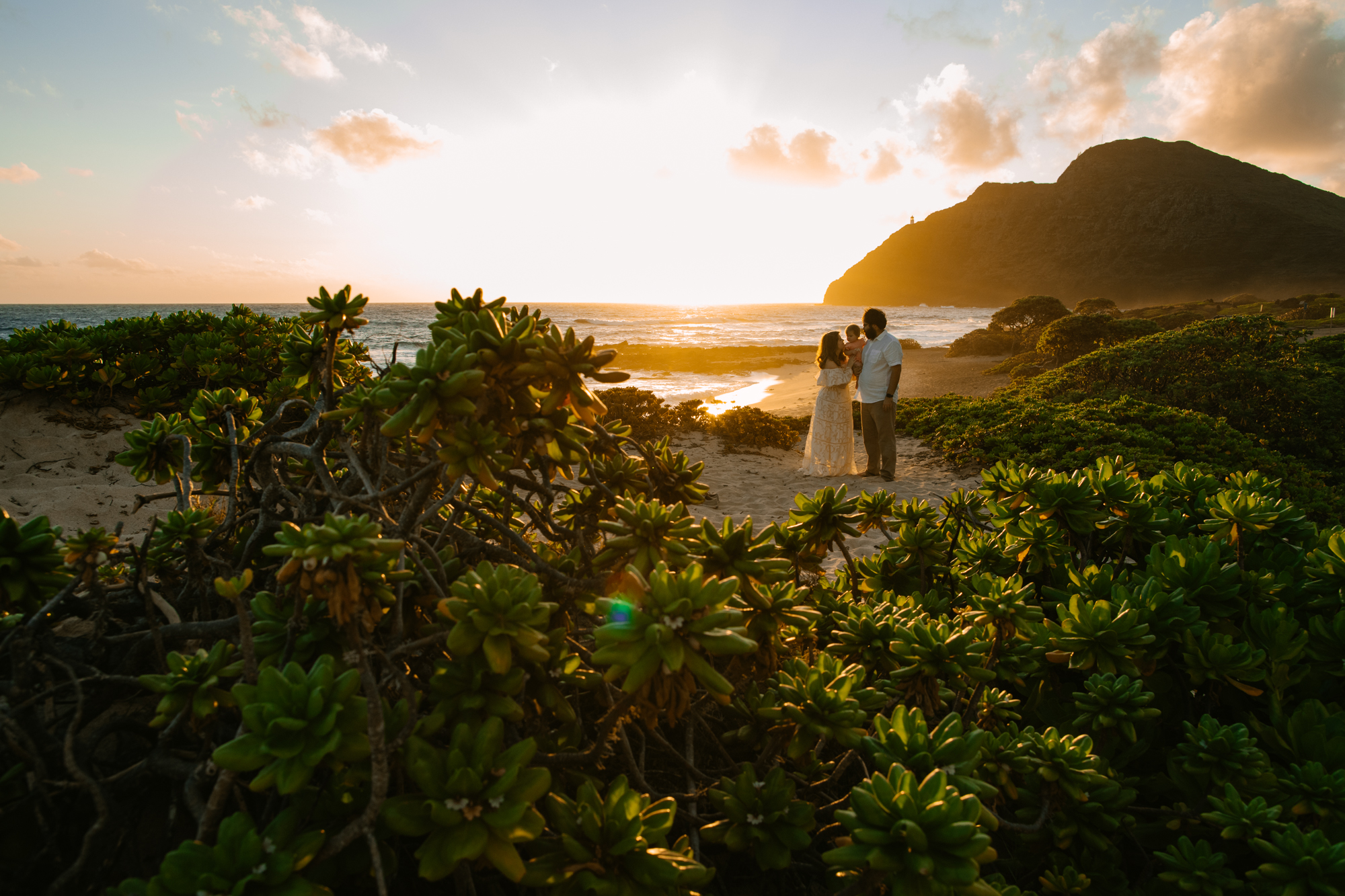 a family with a baby poses at sunrise in oahu