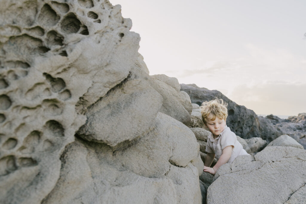 little boy exploring rock formations at kapalua ironwoods on maui