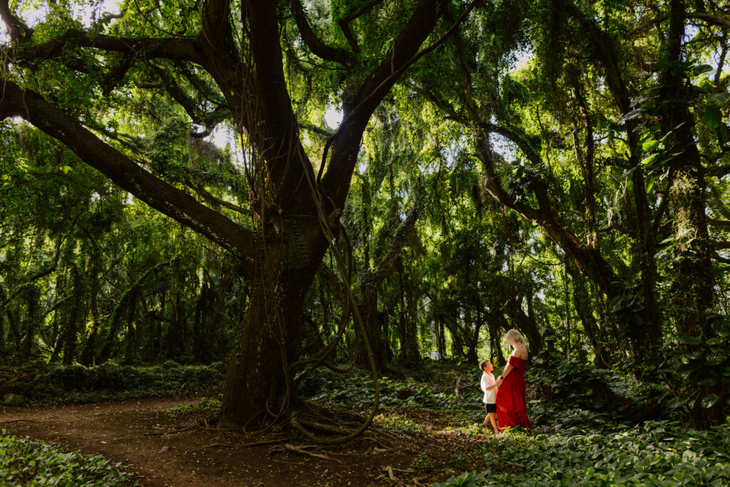 mom and son standing in a ray of llight at maui rainforest during a photoshoot