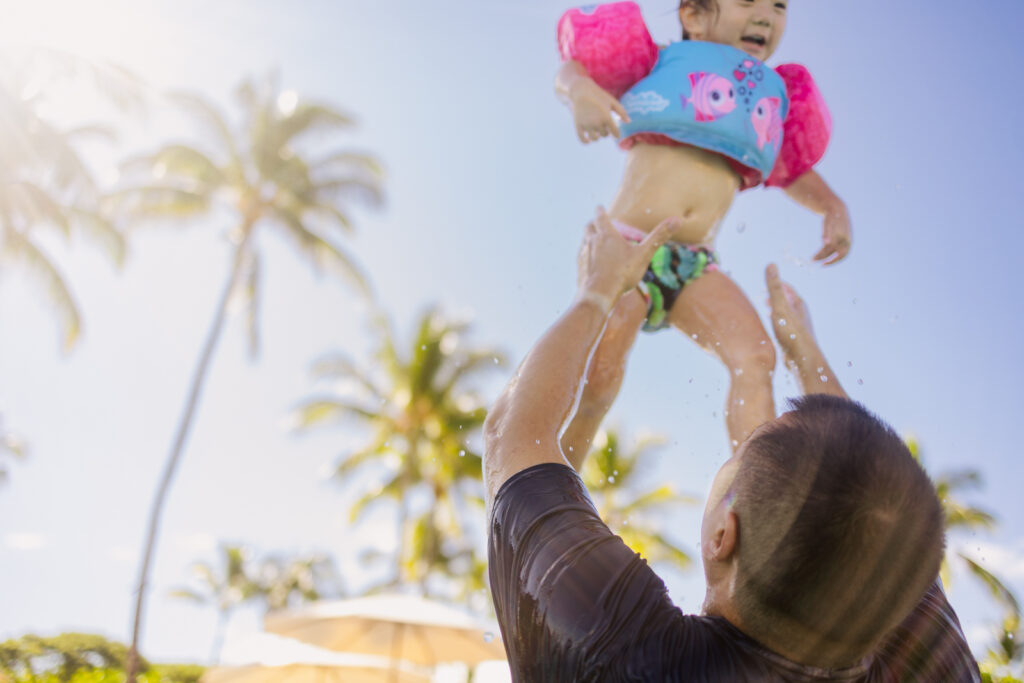 dad throwing toddler in the air during family photos at the four seasons hualalei
