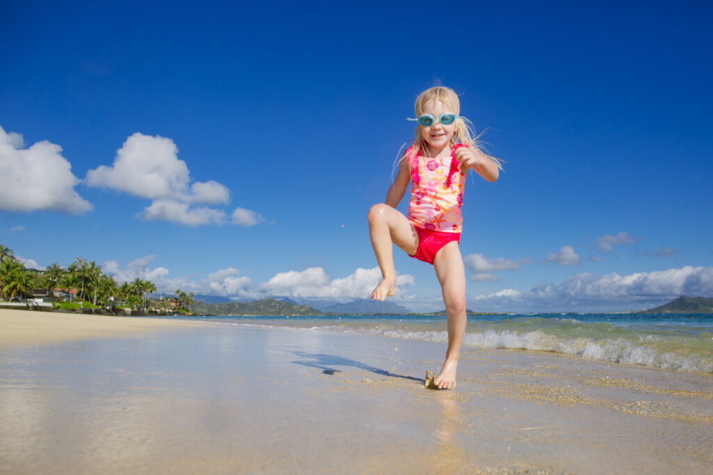 a girl in pink dances against the bright blue of lanikai beach for stress-free family photos in hawaii