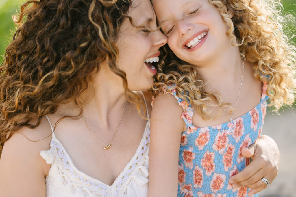 mom and daughter snuggle and laugh during stress-free family photos in hawaii