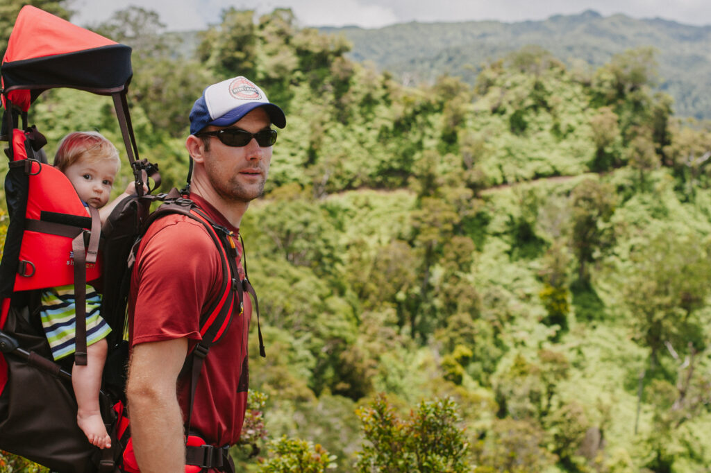dad with baby in carrier hiking in oahu at the start of the poamoho trail
